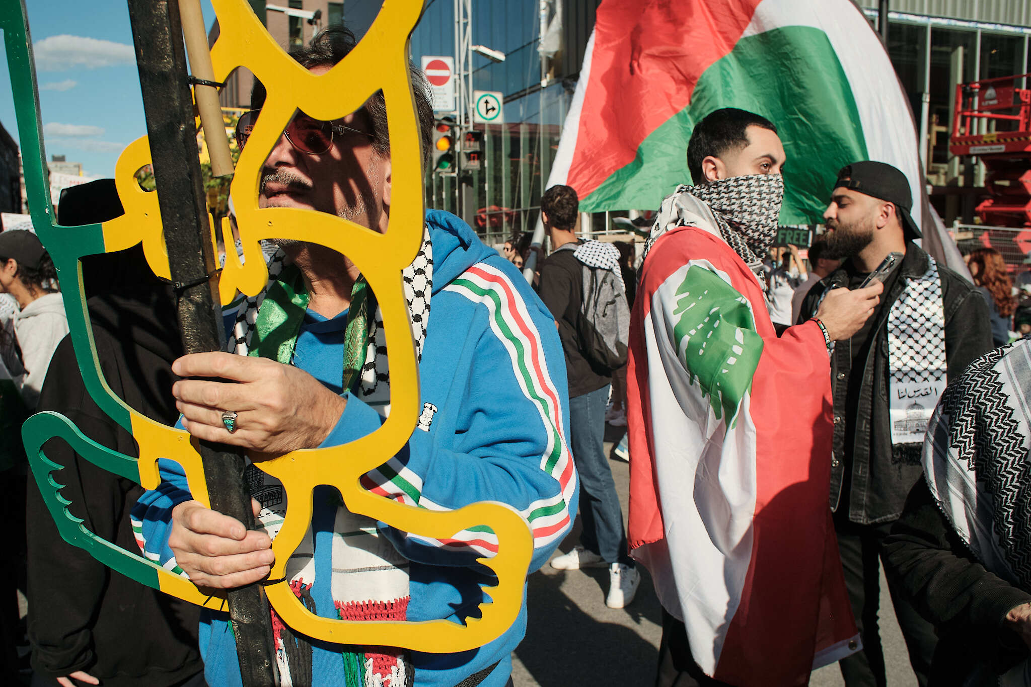 Des manifestant(e)s arborant les couleurs palestiniennes patientent avant le début de la marche.